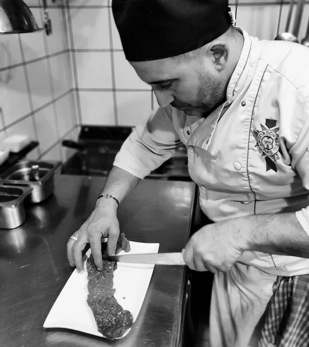 Le chef du Petit Gourmet en cuisine, dressant un plat — formé au Royal Opéra et au George V
